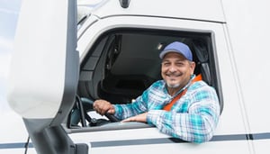 Smiling trucker behind wheel of rig